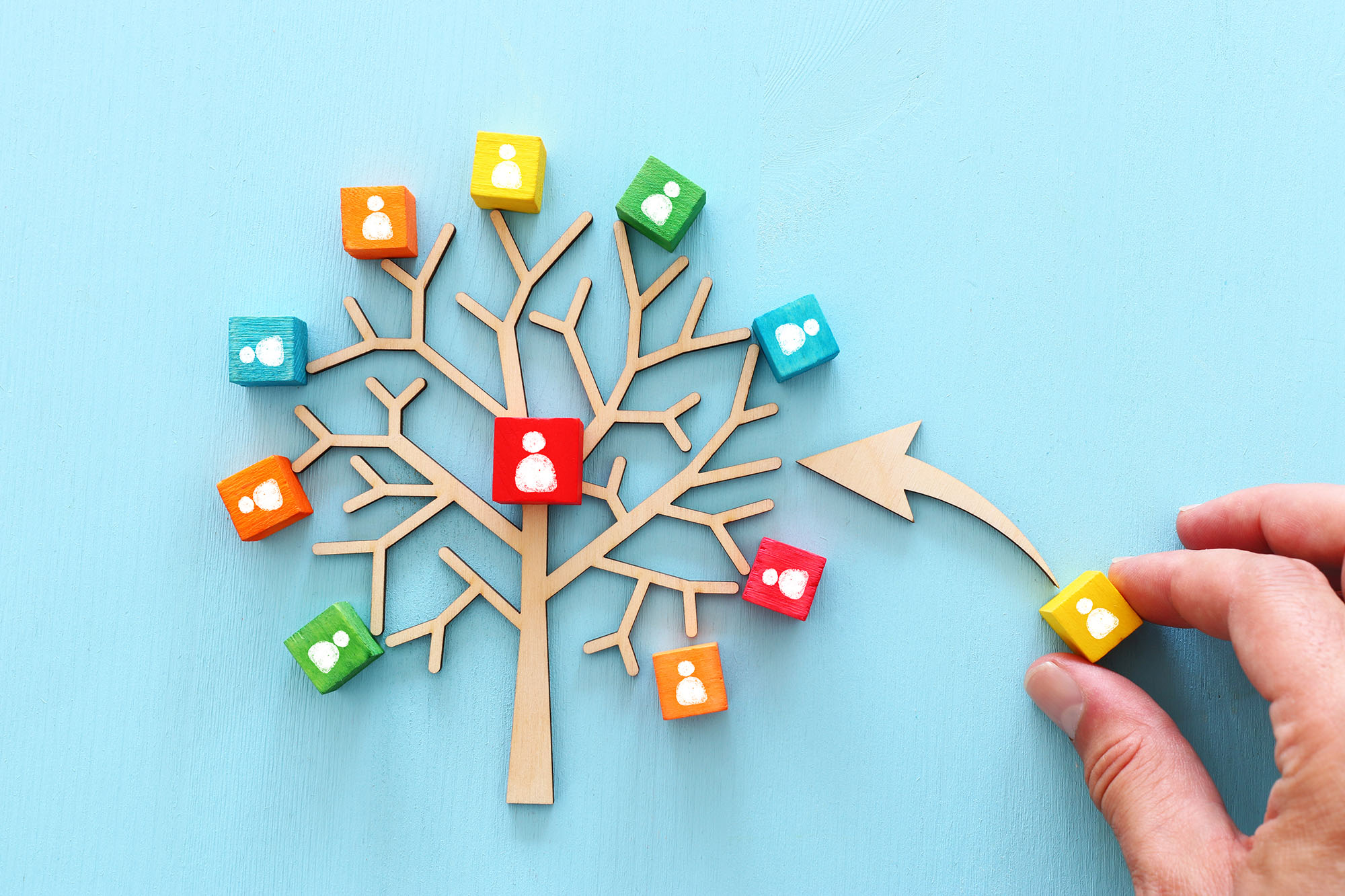 Business image of wooden tree with people icons over blue table, human resources and management concept