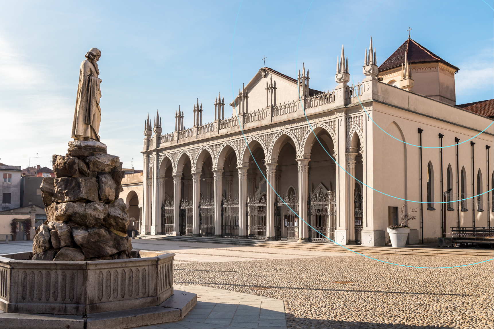 Piazza con statua in pietra e chiesa storica con portico ad archi e decorazioni gotiche sotto un cielo sereno.