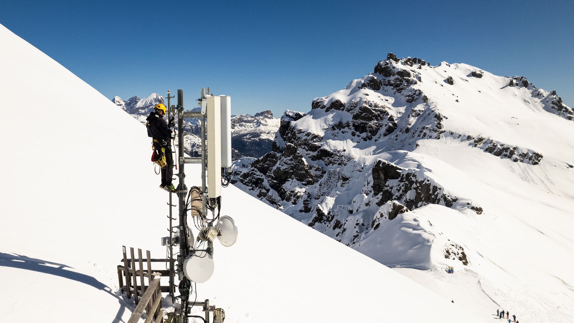 A man setting up a telecommunications tower in the snow-capped mountains