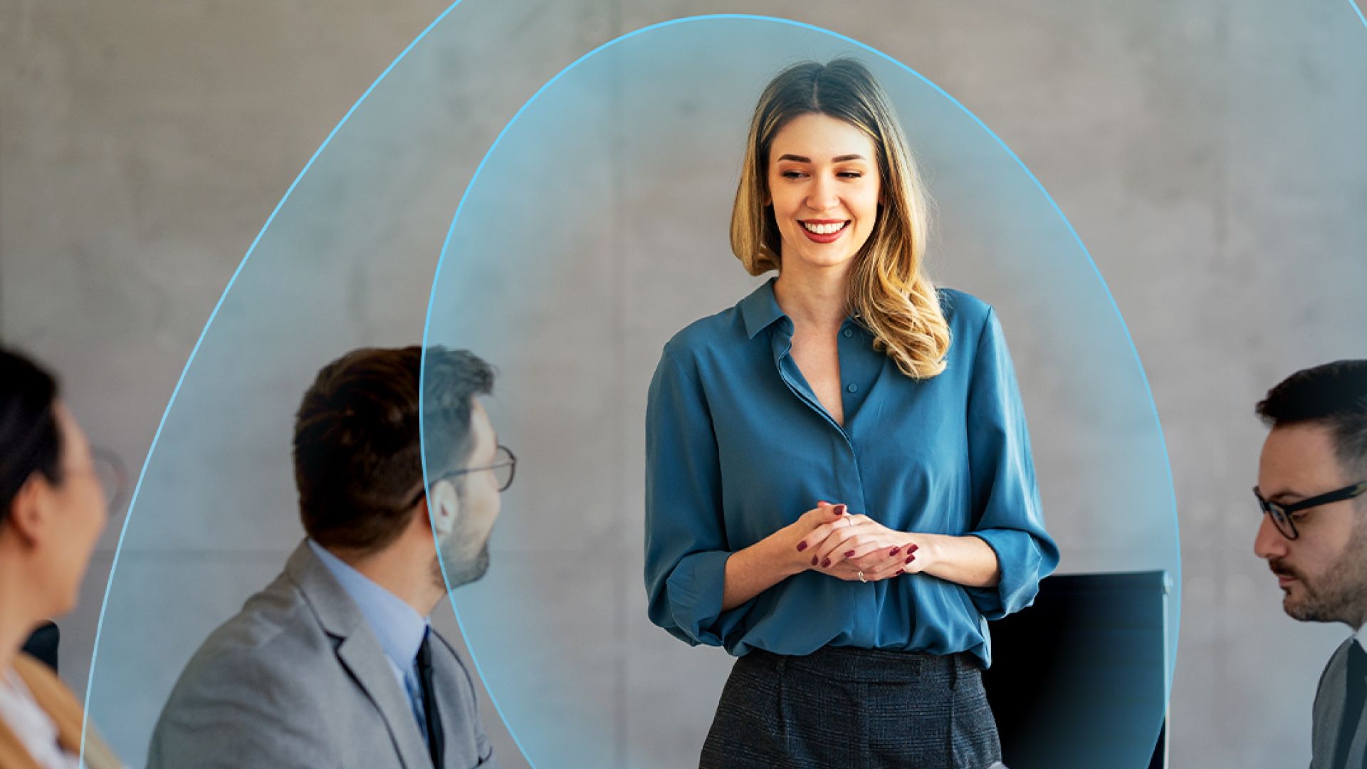 Woman in blue shirt talking while standing in front of colleagues